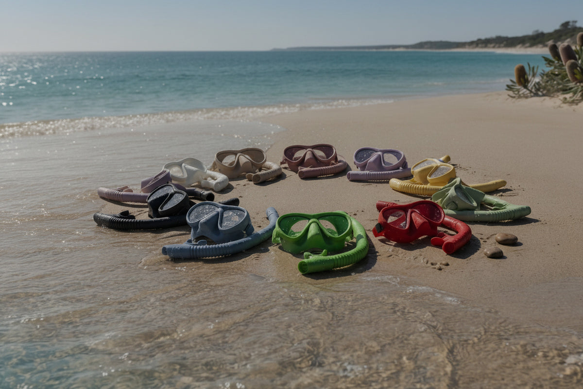 A group of colorful plastic flip-flop sandals arranged on a sandy beach shoreline with turquoise water in the background.